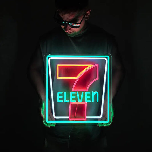 Eine Person hält ein leuchtendes 7-Eleven Neon-Schild in einem dunklen Raum, das Logo spiegelt sich in der Sonnenbrille
