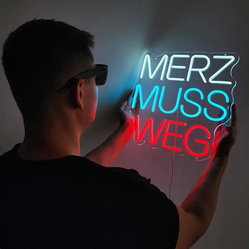 Auffälliger LED-Schriftzug mit politischem Inhalt; Anti-Merz-Protest-Design als leuchtende Wanddekoration.