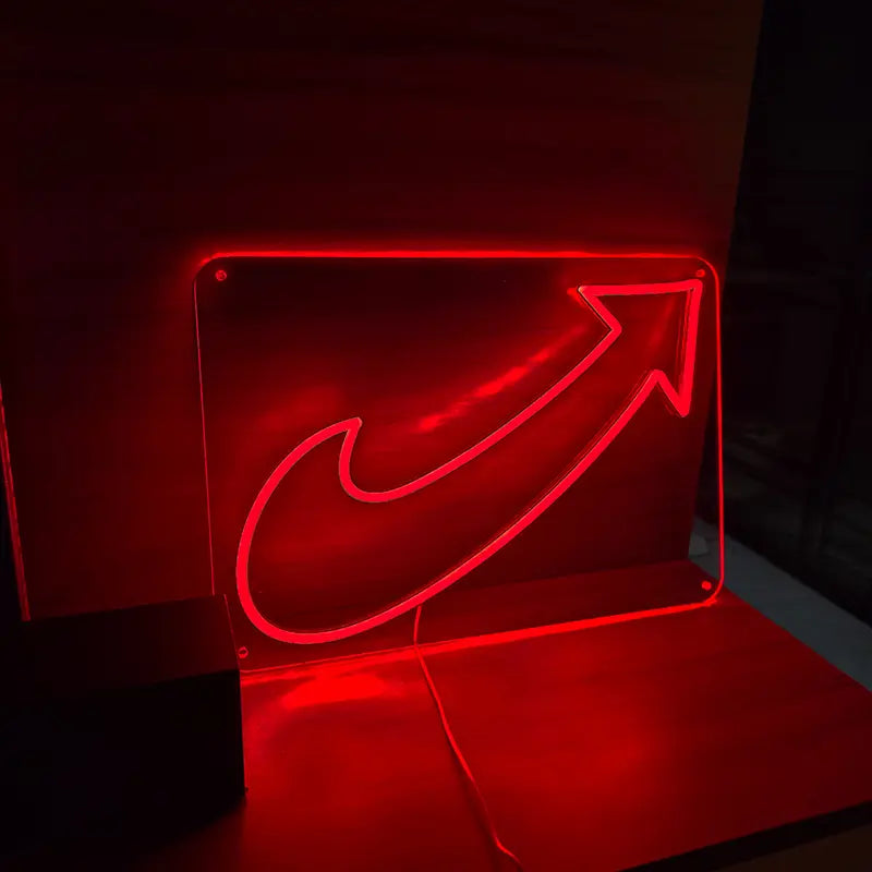 Ein leuchtendes rotes Neon-Schild in Form eines geschwungenen Pfeils auf einer transparenten Acrylplatte
